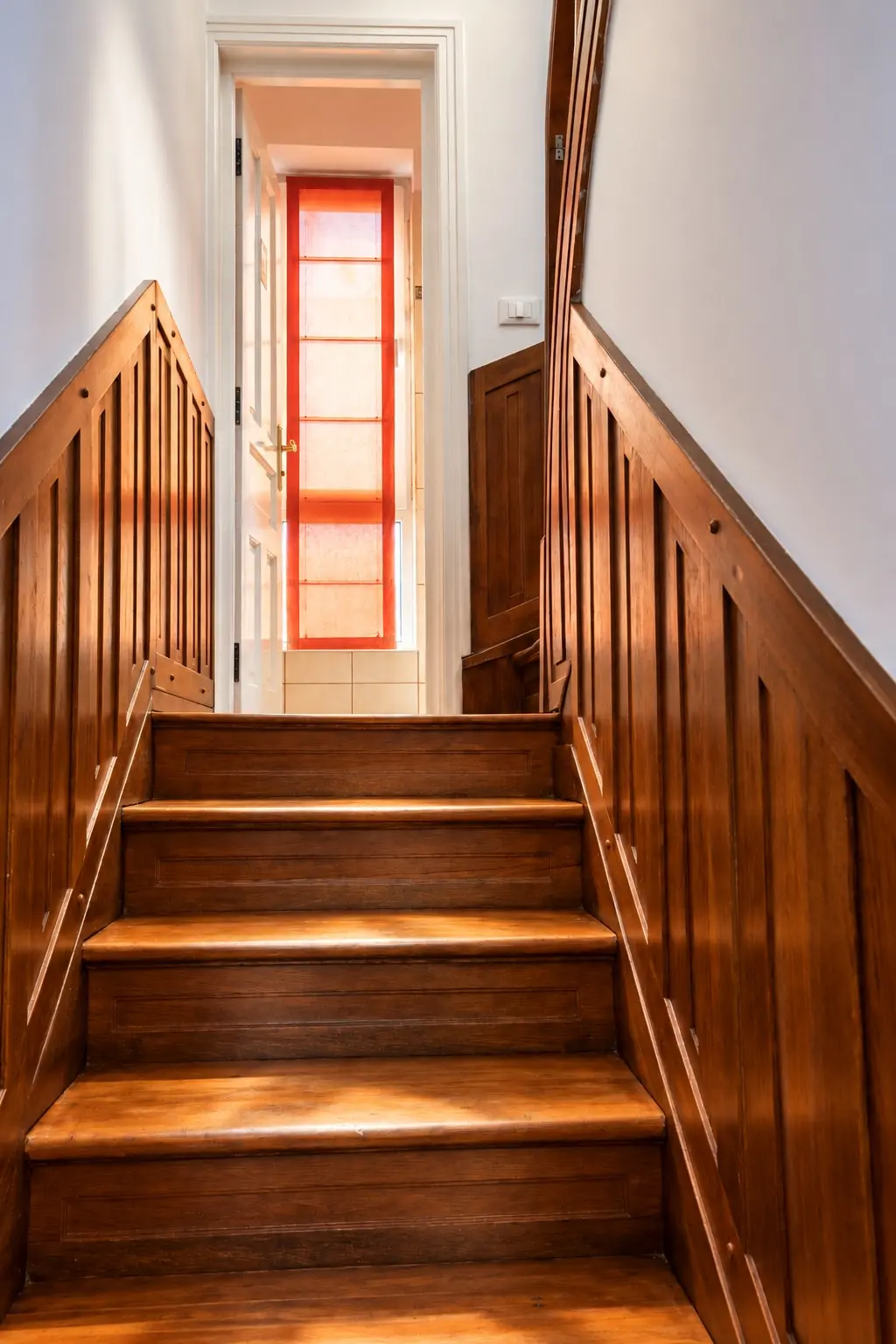 A wooden stairway to a sunlit doorway
